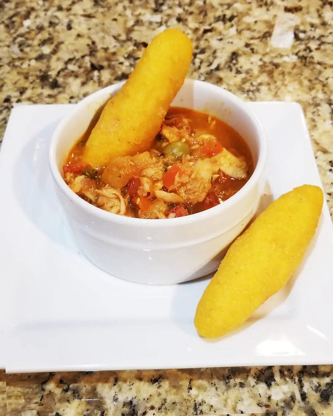 Appetizing plate of salted fish stew, served with cheesy corn fritters