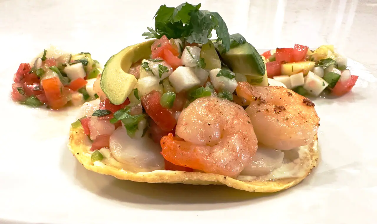 A crispy corn tortilla topped fresh flavors of shrimp, avocado, and salsa
