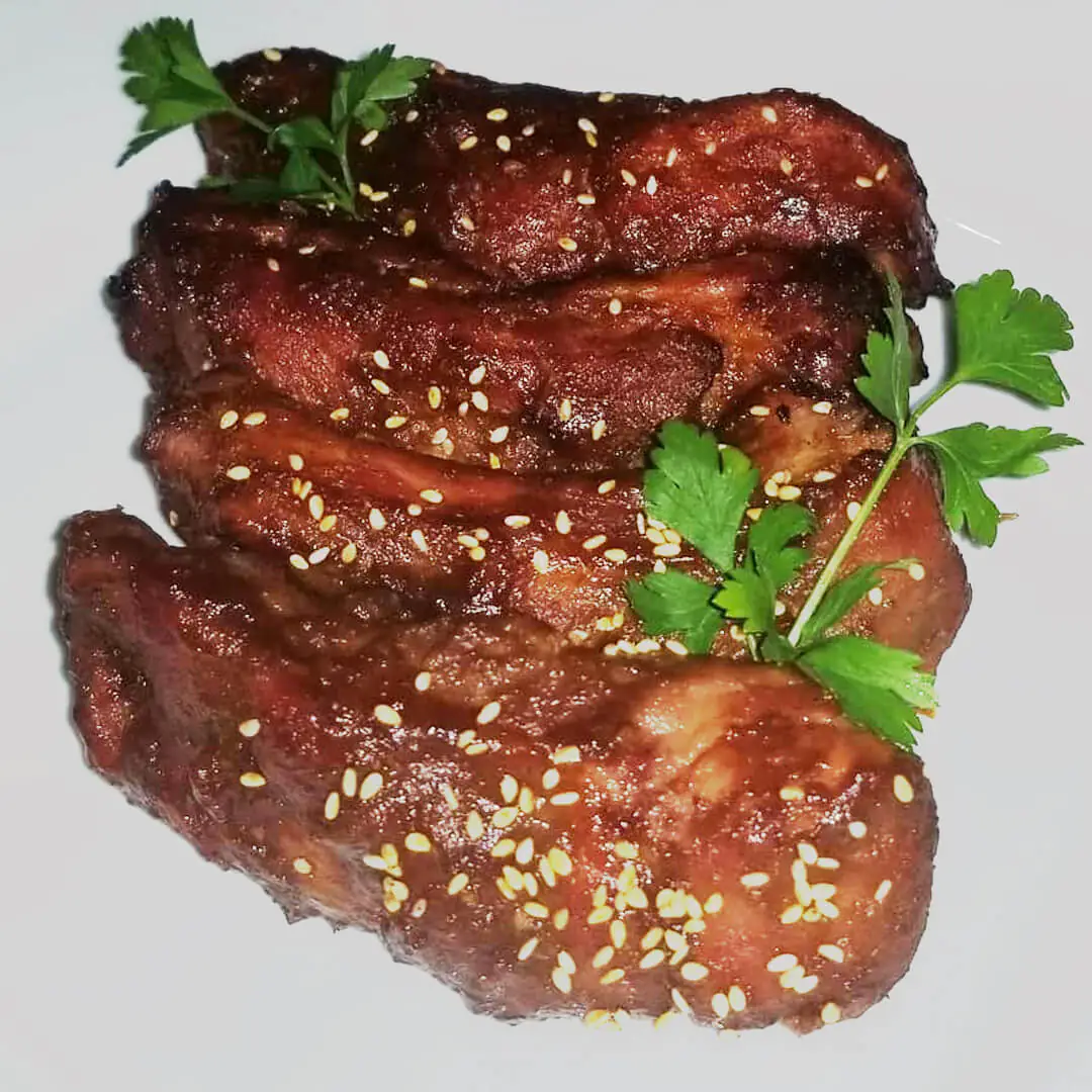 Four delectable ribs, sprinkled with sesame seeds and garnished with fresh parsley